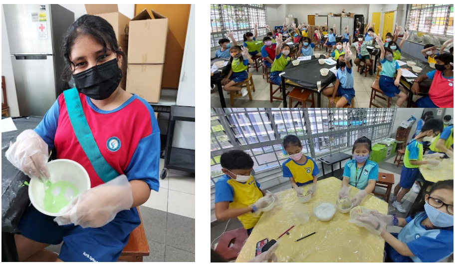 Students wearing masks and gloves participate in a hands-on classroom activity mixing substances in bowls.